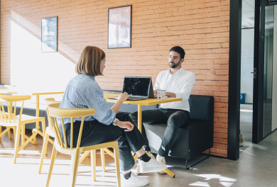 Deux collaborateurs souriant et travaillant devant un écran d'ordinateur. 